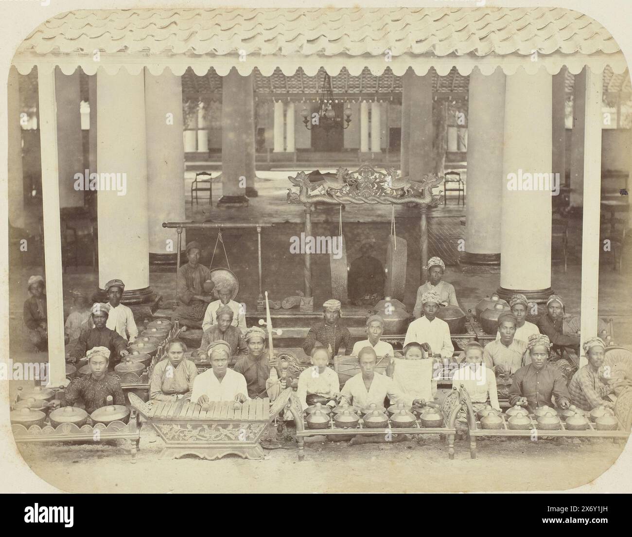 Orchestra gamelan, Un'orchestra gamelan, composta da 23 persone, sedute sotto il tetto di uno spazio coperto con spesse colonne. Parte dell'album fotografico presentato dalla Soerabayasche Association of Sugar Manufacturers a Frederik Beyerinck, residente a Soerabaya., Fotografia, Herman Salzwedel, Soerabayasche Vereeniging van Suikerfabrikanten, Surabaya, 1876 - 1884, supporto fotografico, stampa albume, altezza, 21,3 cm x larghezza, 27,5 cm Foto Stock