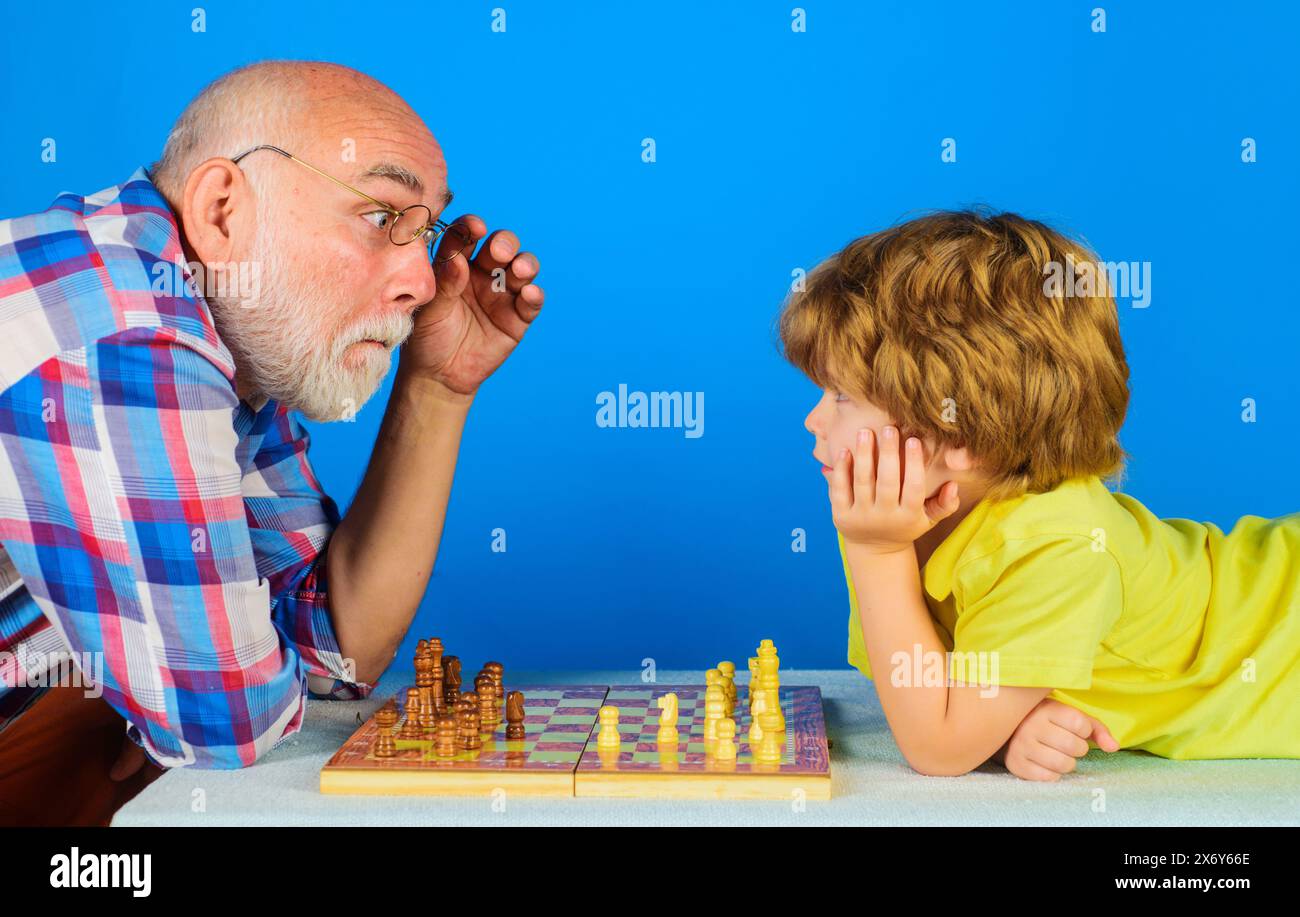 Nipote che gioca a scacchi con nonno. Giochi e attività per bambini. Nonno che insegna a nipotino giocare a scacchi. Gioco da tavolo. Scacco matto. Bambino piccolo Foto Stock