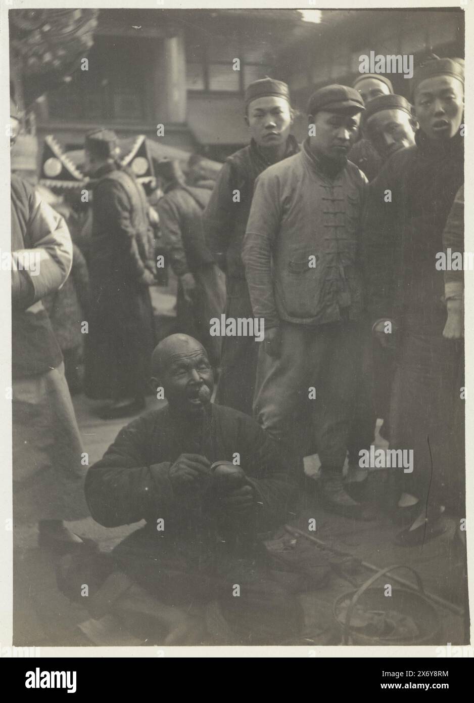 Un abitante nella città cinese (titolo su oggetto), venditore sul mercato di Shanghai. Parte dell'album fotografico di Dolph Kessler con le foto che ha realizzato durante il suo soggiorno in Inghilterra e in un viaggio nel mondo ha intrapreso come segretario di Henri Deterding (direttore della Royal Oil) nelle Indie Orientali olandesi, in Giappone, in Cina e negli Stati Uniti, tra il 1906 e il 1908. Geldolph Adriaan Kessler (Dolph), Shanghai, dopo il 16 marzo 1908 - prima del 2 aprile 1908, cartone, stampa in gelatina argento, altezza, 100 mm x larghezza, 74 mm, altezza, 363 mm x larghezza, 268 mm Foto Stock