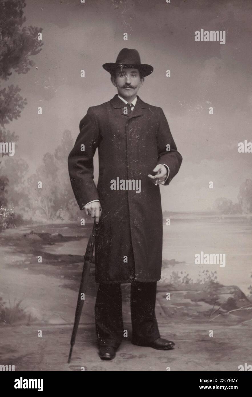 Ritratto di un uomo sconosciuto che indossa un cappello, una giacca e un ombrello, fotografia di un armadietto, David van der Heide, (menzionato sull'oggetto), Amsterdam, 1901 - 1923, cartone, altezza, 140 mm x larghezza, 98 mm Foto Stock