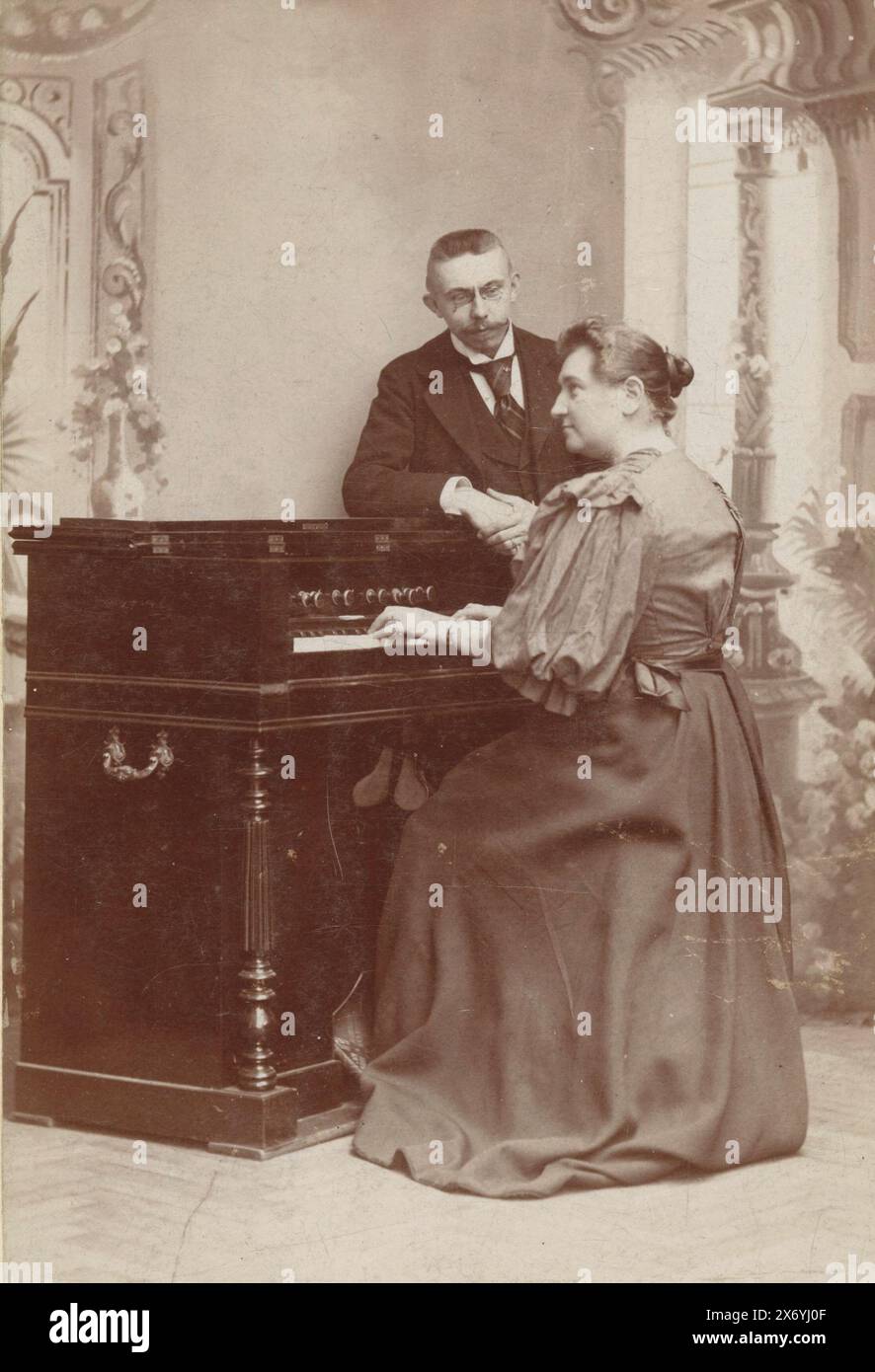 Ritratto di una donna che suona l'organo e di un uomo che guarda, fotografia di un armadietto, Léonard Hubert Zeyen, (menzionato sull'oggetto), Luik, c. 1890 - in o prima del 1915, cartone, altezza, 137 mm x larghezza, 92 mm Foto Stock