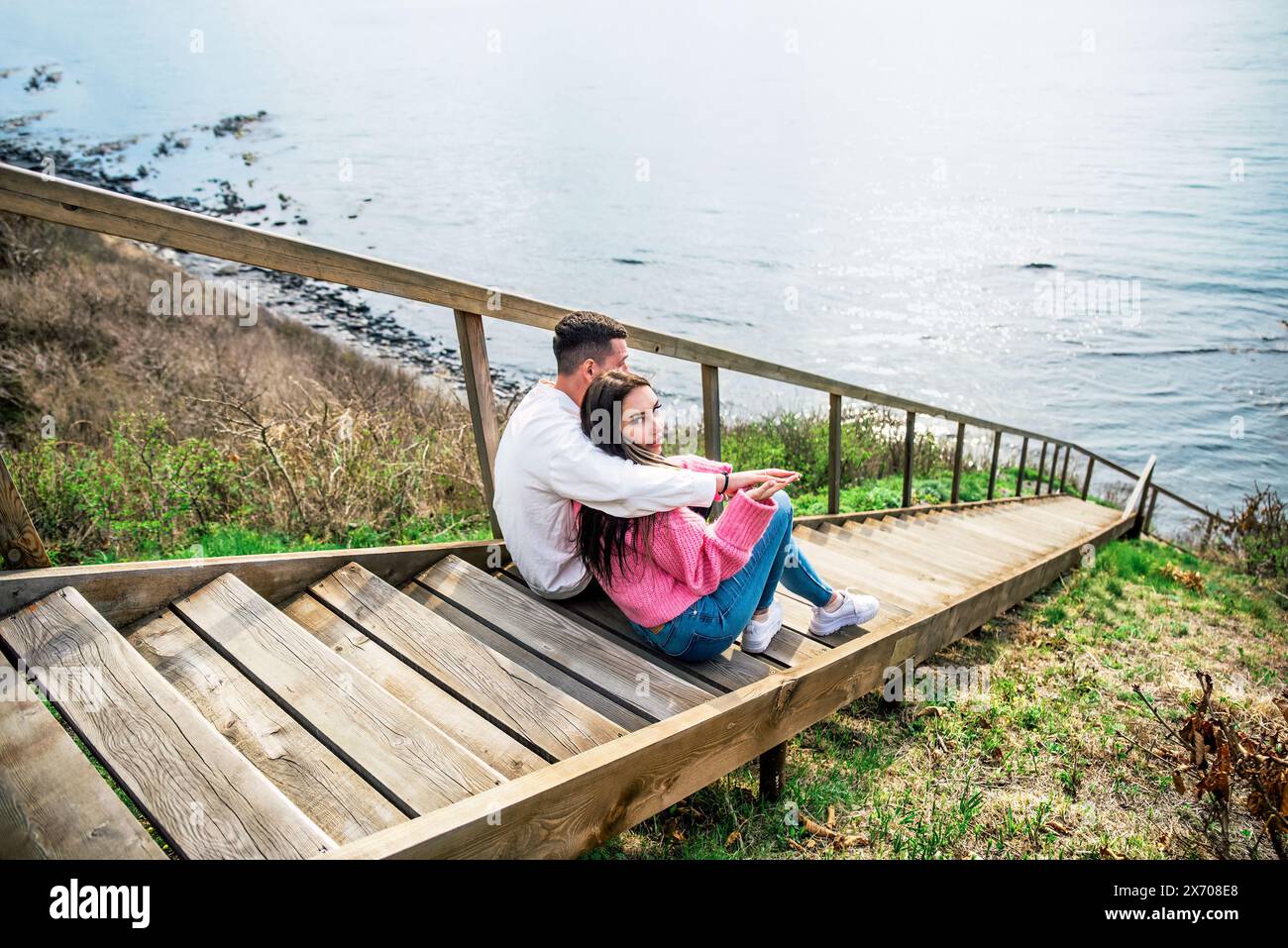 Giovane coppia sposata seduta sulle lunghe scale di legno e guardando il mare giapponese Foto Stock
