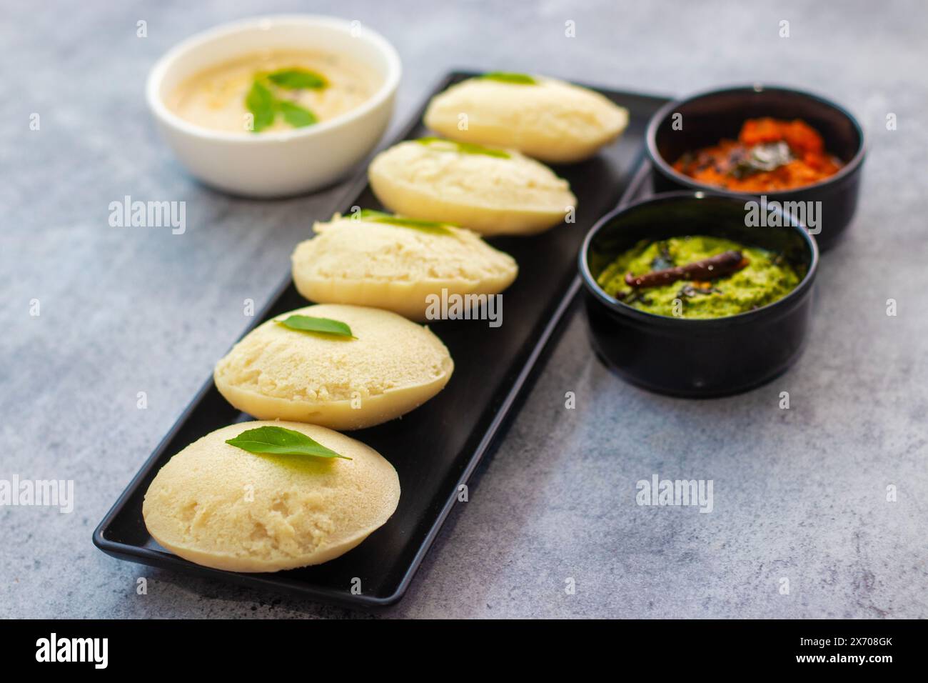 Focalizzazione selettiva del famoso cibo dell'India meridionale 'Idli vadaa' con Sambar e Chatney. Foto Stock