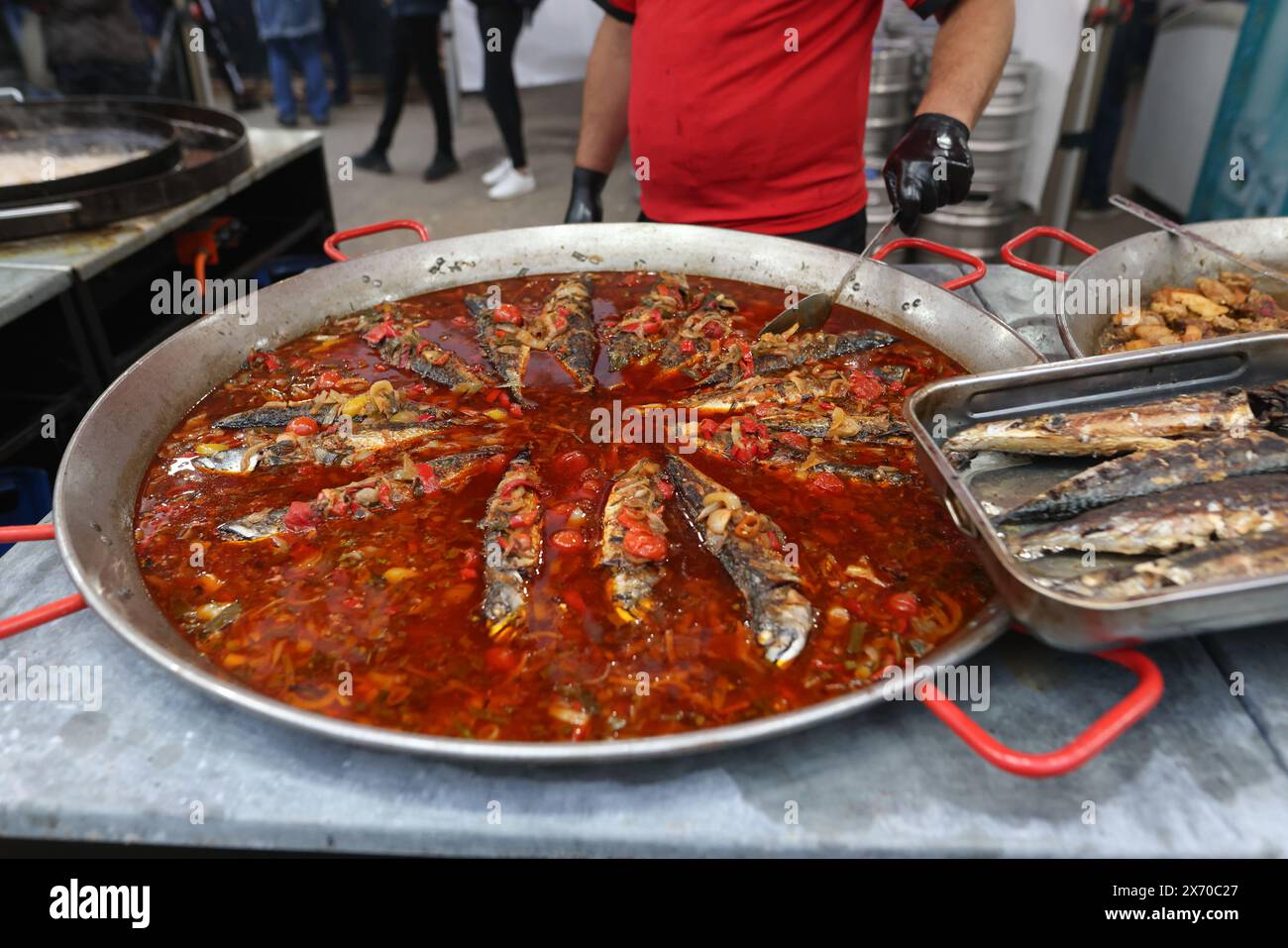 Il pesce viene cucinato in una padella enorme durante un festival gastronomico all'aperto. Foto Stock