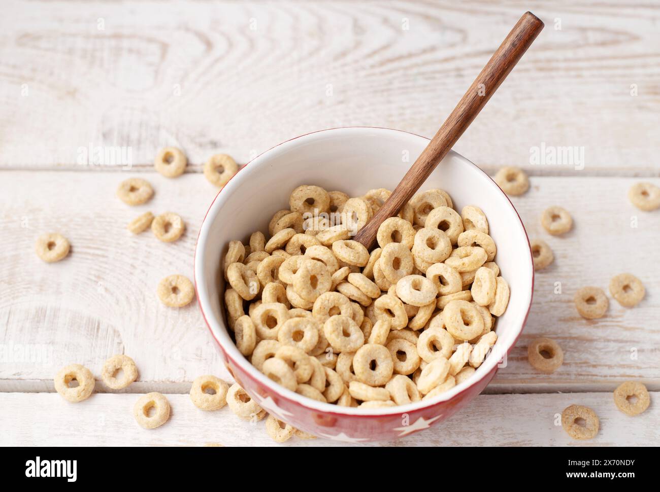 sani anelli di cereali su uno sfondo di legno chiaro in un piatto e sparsi sul tavolo. mattina, mangia. Colazione sana per bambini. Muesli secchi Foto Stock