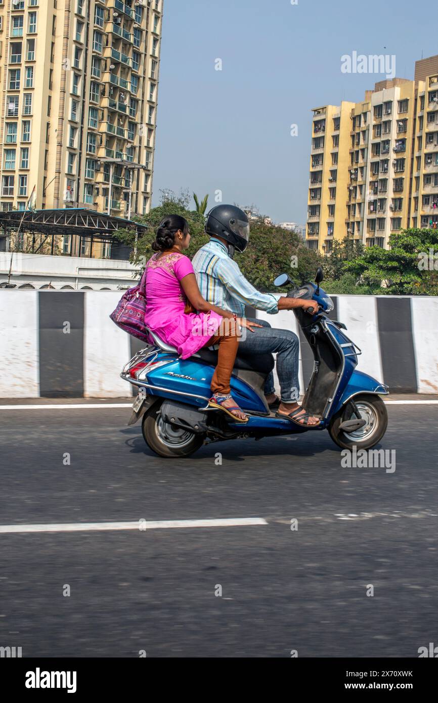 coppia indiana che guida con una donna di scooter seduta sul sedile posteriore all'aperto Foto Stock