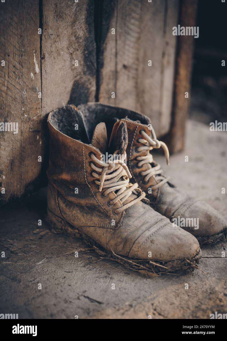 Stivali isolati fangosi da fattoria. Primo piano di un paio di stivali in pelle indossati con fango. Un aspetto rétro per il lavoro rurale Foto Stock