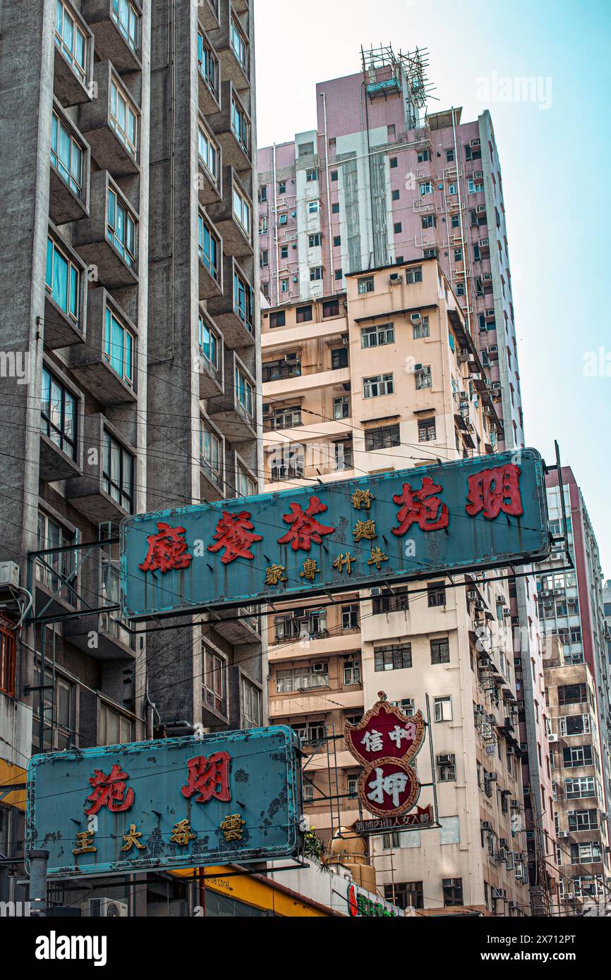 Una delle innumerevoli strade trafficate di Hong Kong che mostra i cartelli che pendono sopra la testa. Hong Kong, Cina, Asia. Foto Stock