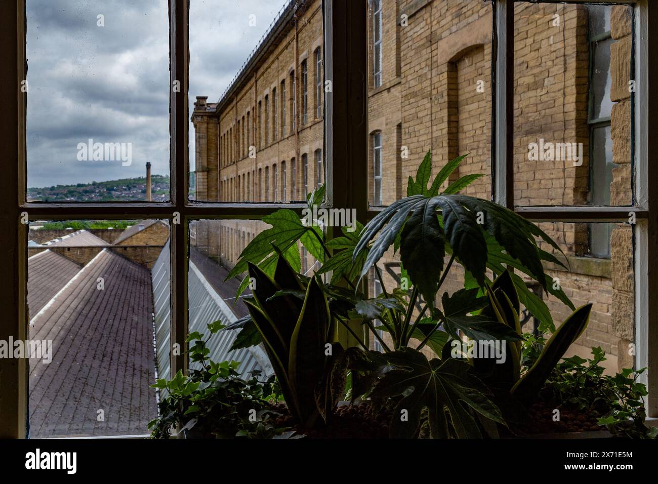 Vista dalla finestra del secondo piano da Salts Mill a Saltaire. La vista si affaccia sul tetto del piano inferiore del mulino verso Wrose. Foto Stock