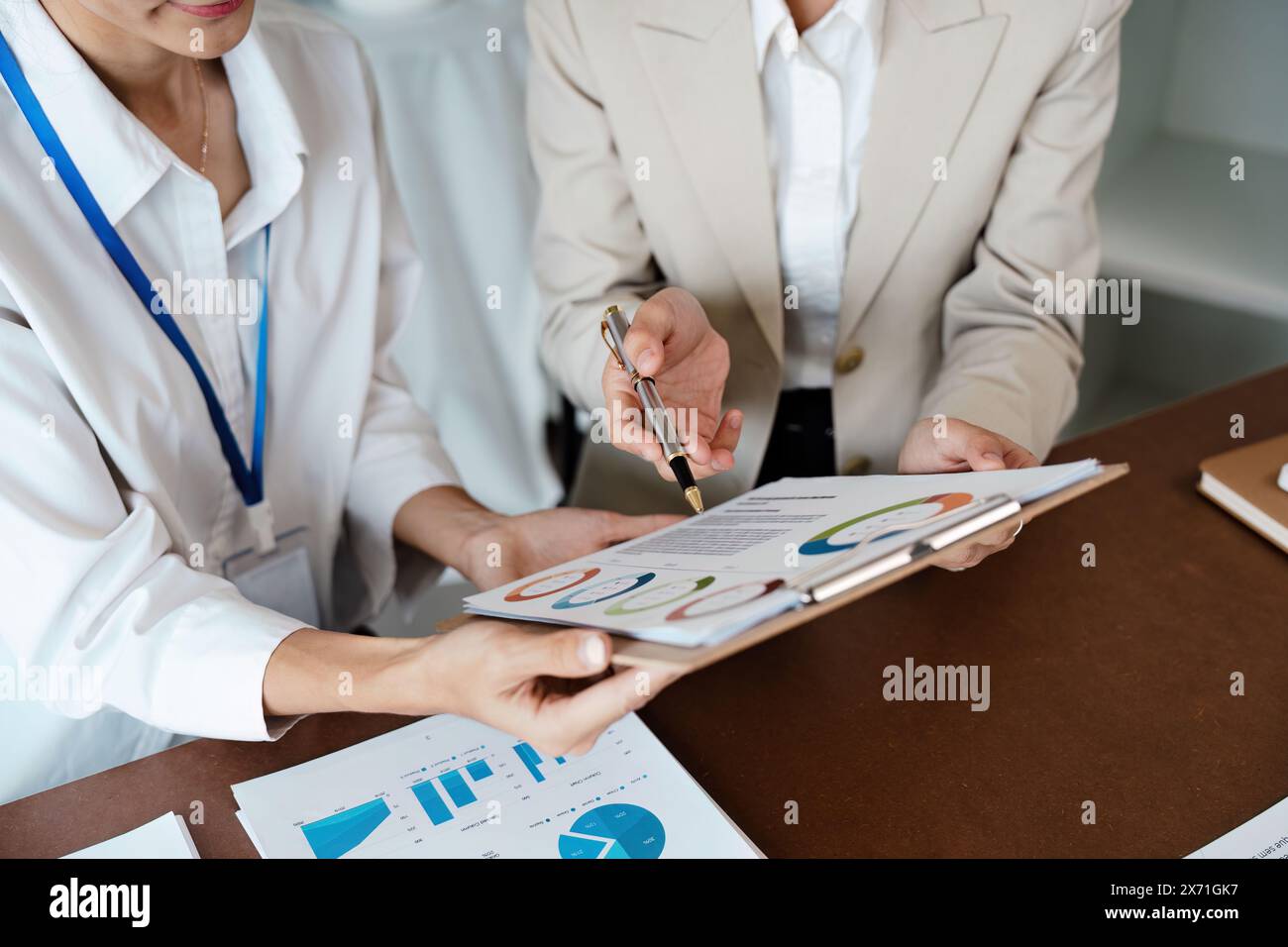 Una donna d'affari collaborativa si riunisce per analizzare grafici finanziari e grafici sulla scrivania per la pianificazione strategica Foto Stock