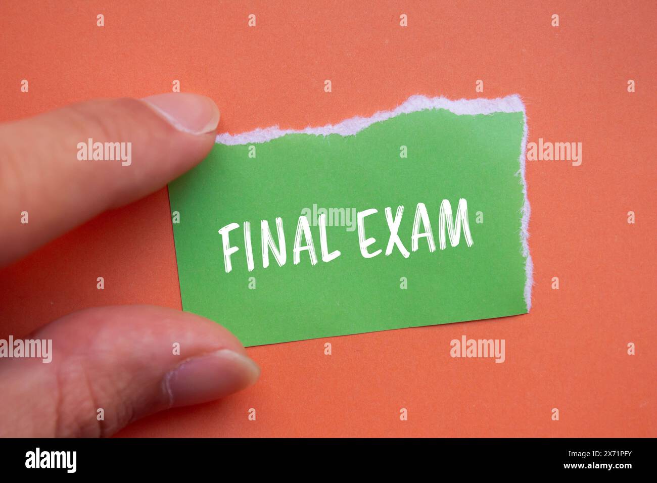 Parole per l'esame finale scritte su un foglio di carta verde strappato con sfondo arancione. Simbolo dell'esame finale concettuale. Copia spazio. Foto Stock