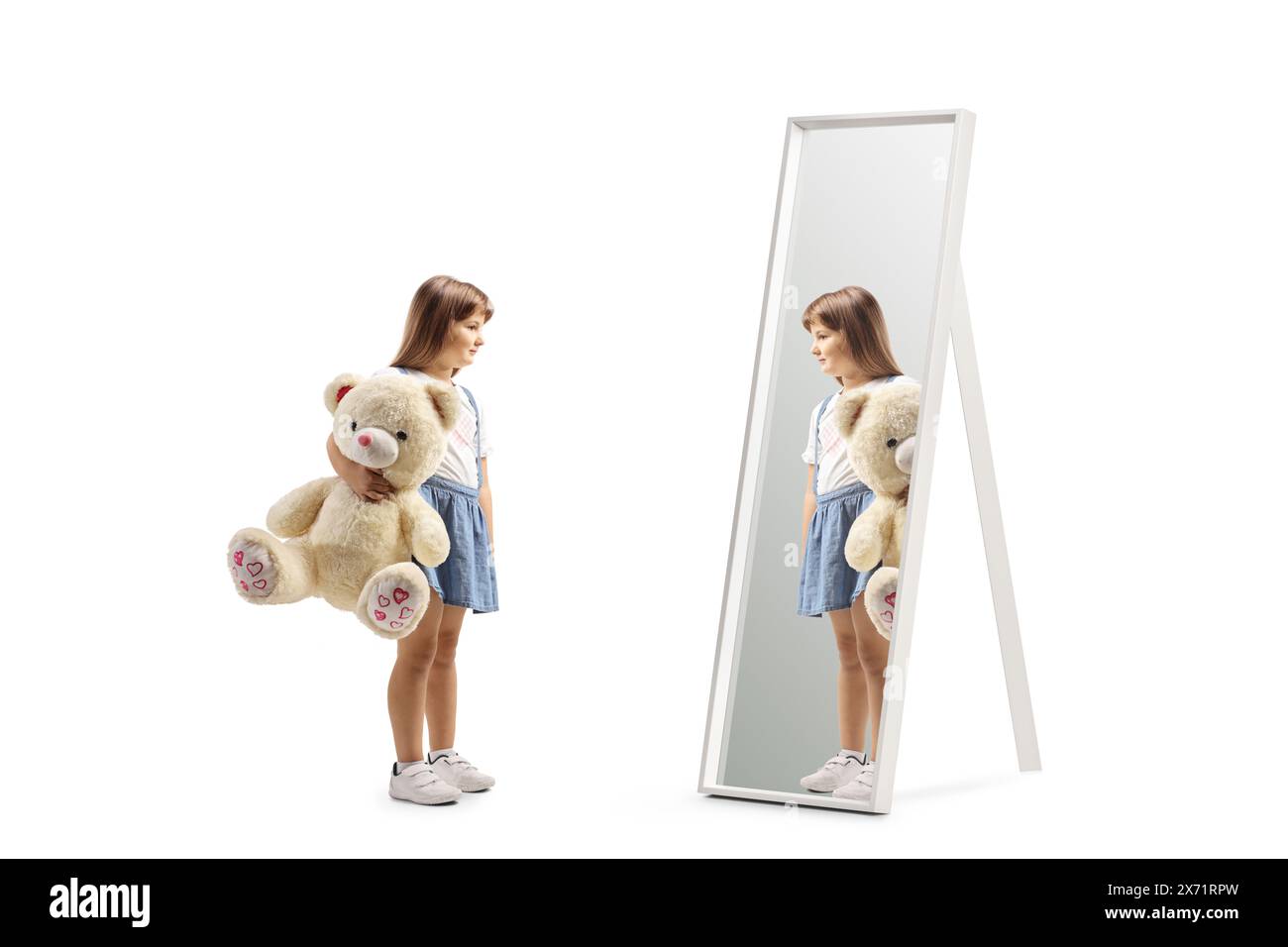 Ragazza che tiene in mano un grande orsacchiotto e guarda uno specchio isolato su sfondo bianco Foto Stock