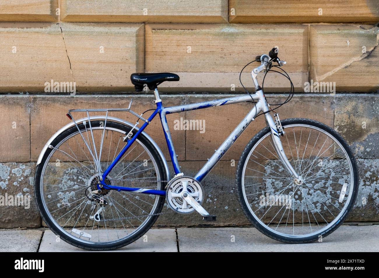 Bicicletta appoggiata contro un muro di pietra. Foto Stock