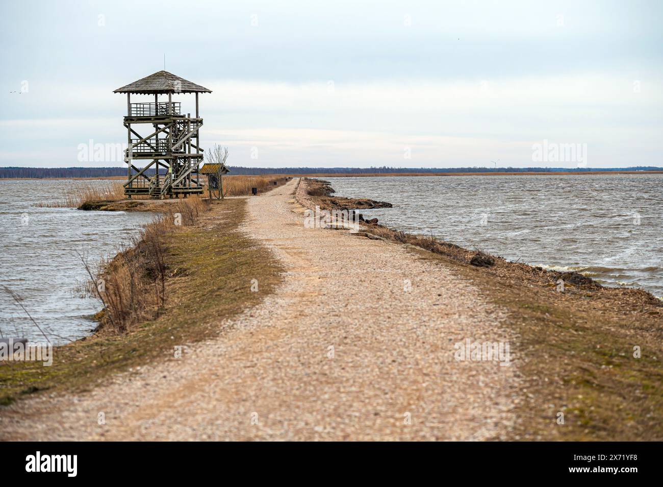Una strada si estende verso una torre d'acqua da un corpo d'acqua. Liepaja, Lettonia Foto Stock