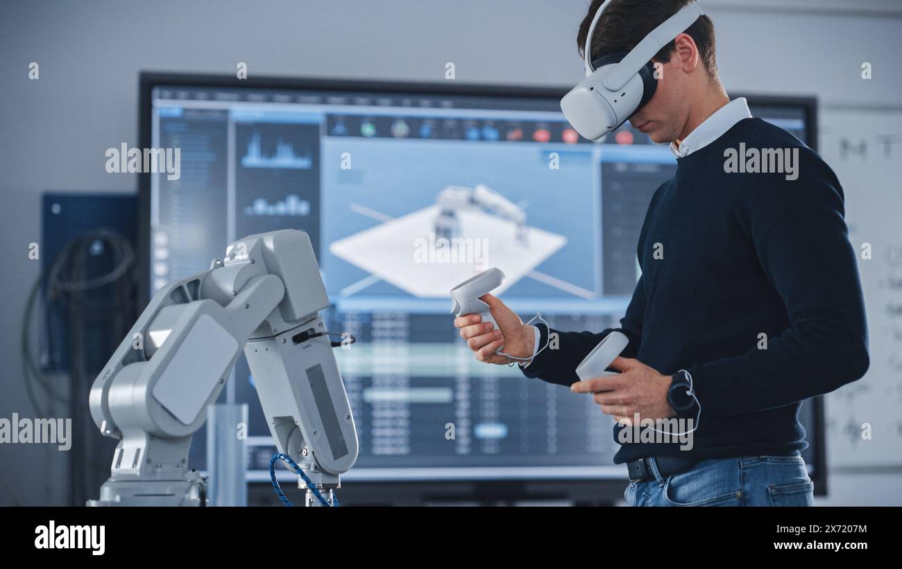 Ingegnere meccanico studente che indossa cuffie per realtà virtuale e controller di tenuta, utilizza la tecnologia VR per la progettazione industriale, lo sviluppo e la prototipazione nella robotica. Concetto High Tech Foto Stock