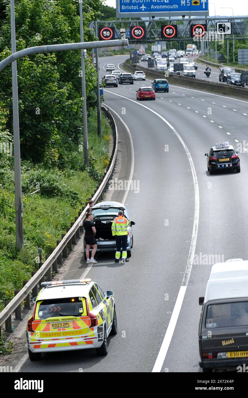 Bristol, Regno Unito. 17 maggio 2024. Un'auto in avaria sulla corsia interna dell'autostrada gestita aumenta i problemi dei conducenti su un'autostrada già congestionata. Senza una spalla dura, il conducente ha dovuto chiedere aiuto e poi sedersi su un tratto molto affollato dell'autostrada. Un agente del traffico e' arrivato entro 10 minuti. La fuga del fine settimana soleggiata aveva già causato congestione con Matrix Signs che limitava la velocità a 40/50mph sulla M5 tra gli svincoli 15/16 e 17 a Bristol. Le autostrade inglesi riportano velocità negli anni '20, il che è normale in un venerdì soleggiato quando la gente si dirige a sud verso Devon e Cornovaglia. Credito Foto Stock