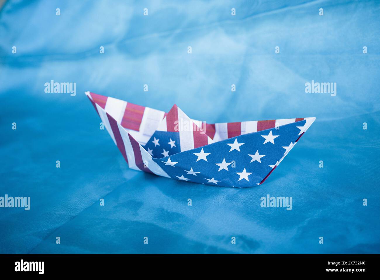 Barca di carta con bandiera americana su sfondo blu. Columbus Day Concept. Foto Stock