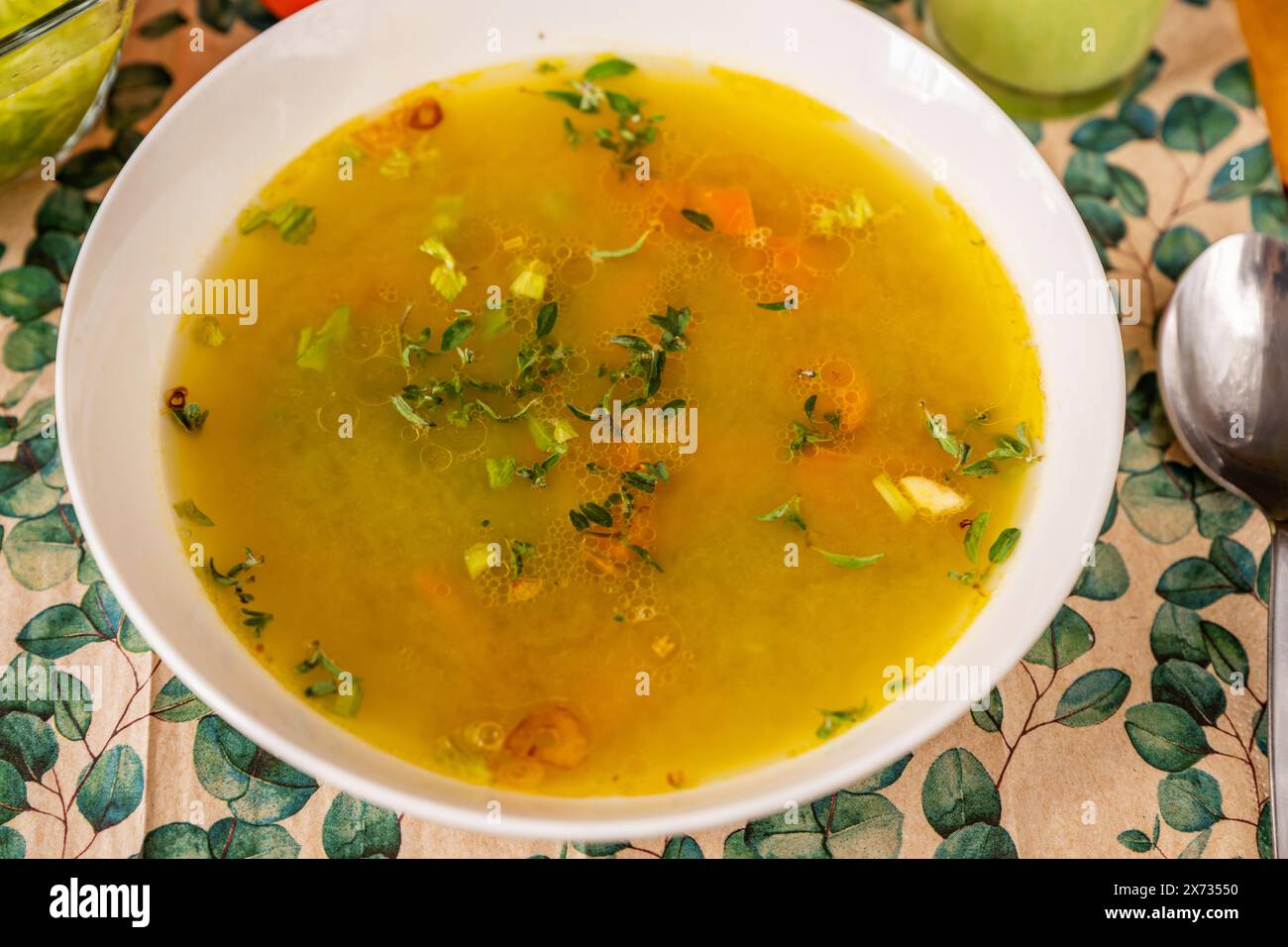 Brodo vegetale denso con erbe nel piatto bianco, cucchiaio sul tavolo, primo piano. Foto Stock