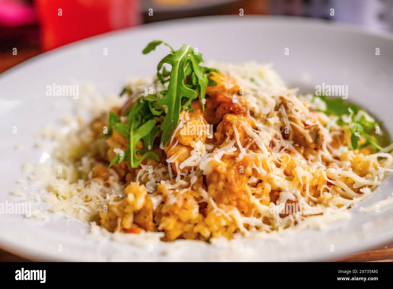 Risotto con pezzetto di carne di pollo con curcuma, formaggio grattugiato e foglia di rucola, primo piano. Foto Stock