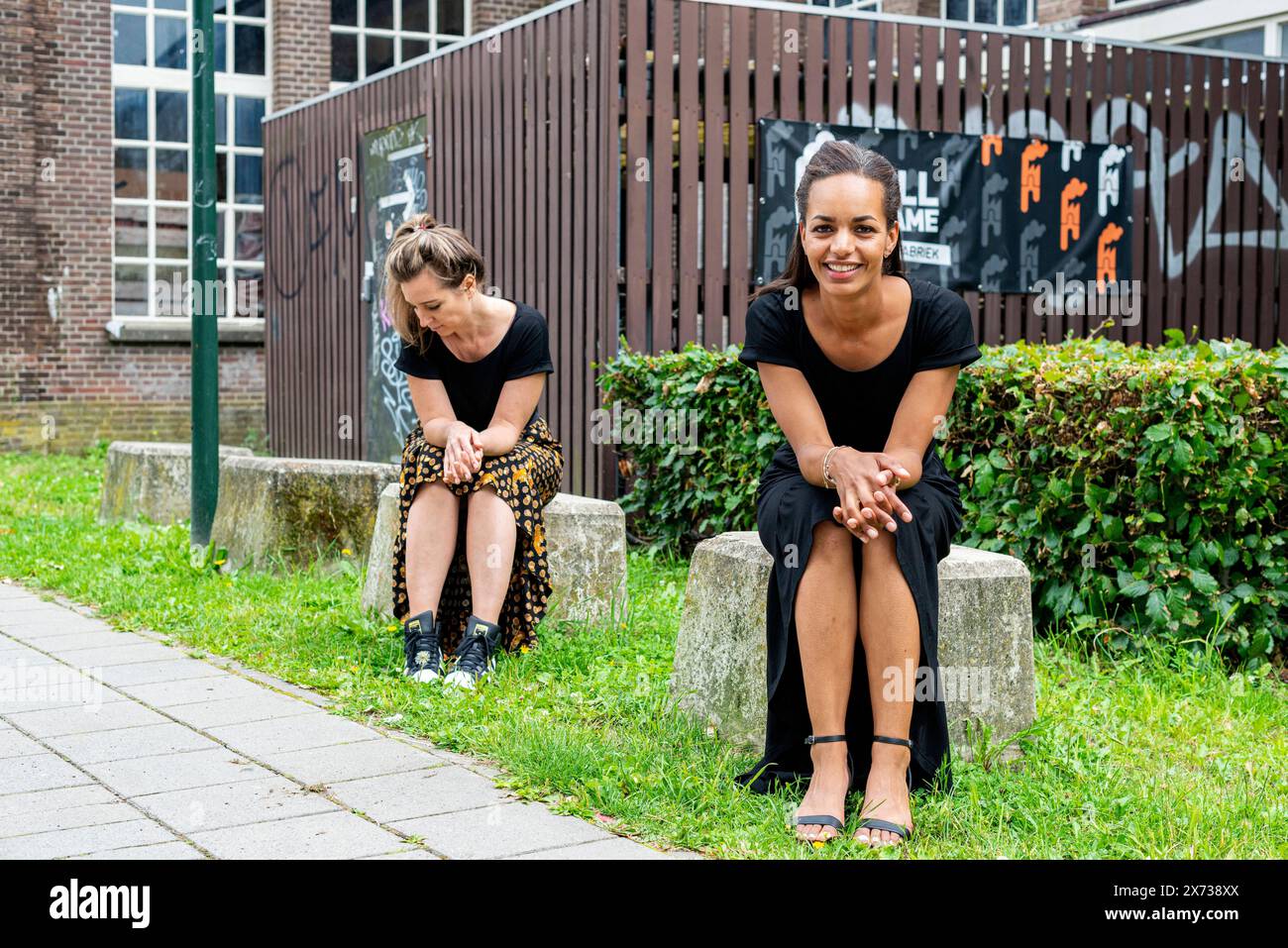 Histoire's Fashion due stilisti di moda femminili, seduti su un cubo di cemento all'interno di un ex stabilimento industriale. Tilburg, Paesi Bassi. MRYES Tilburg Foto Stock