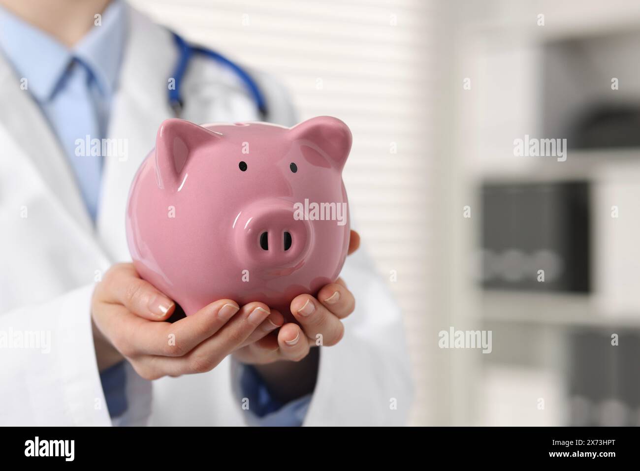Dottore con salvadanaio rosa al chiuso, primo piano. Spazio per il testo Foto Stock