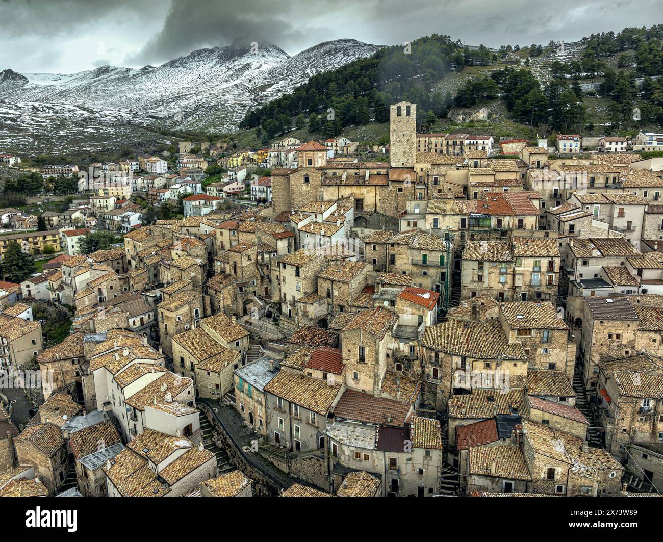 Vista aerea dell'antico borgo medievale di Castel del Monte con la catena innevata del Gran Sasso alle sue spalle. Castel del Monte, Abruzzo Foto Stock