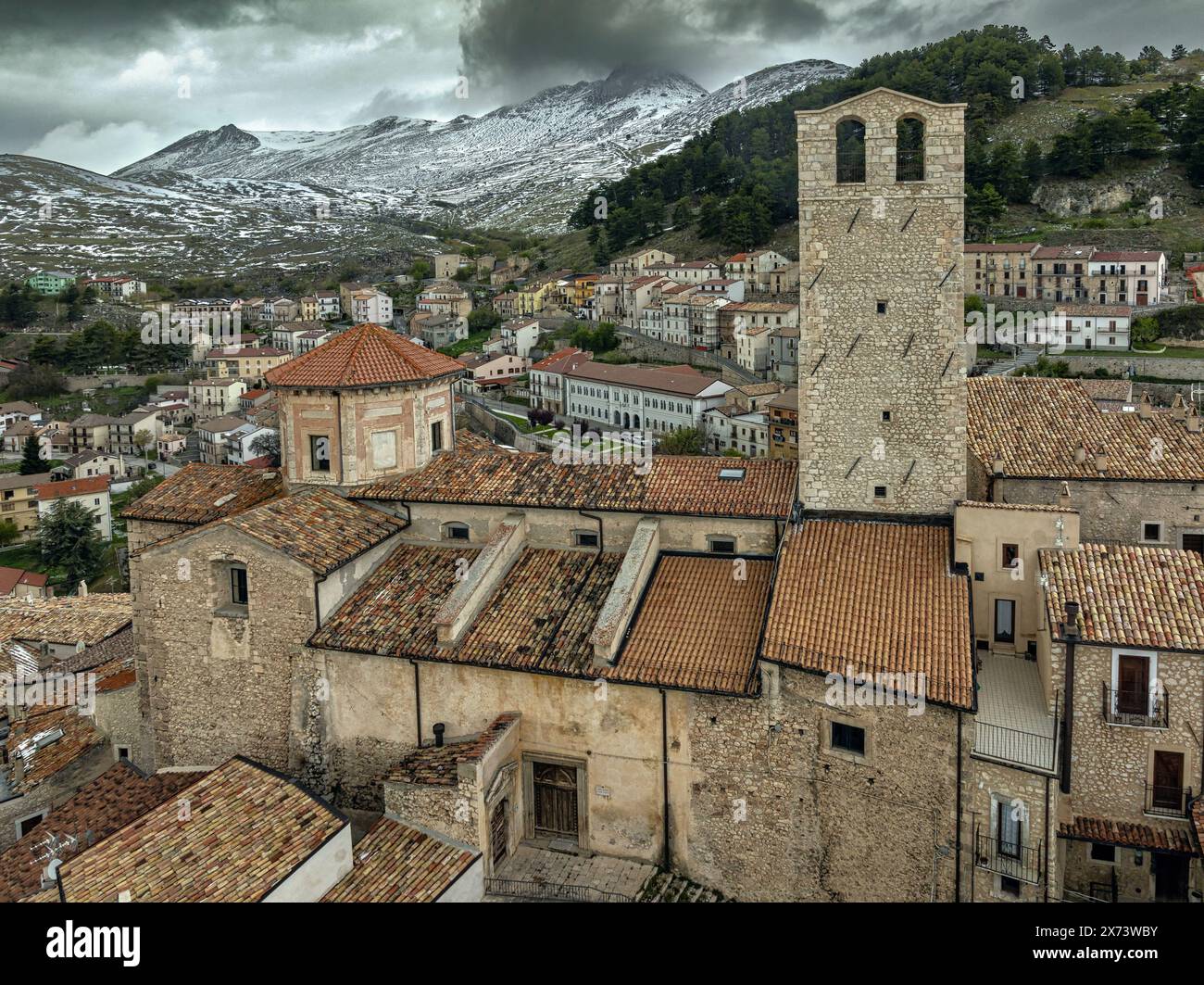 Vista aerea dell'antico borgo medievale di Castel del Monte con la catena innevata del Gran Sasso alle sue spalle. Castel del Monte, Abruzzo Foto Stock