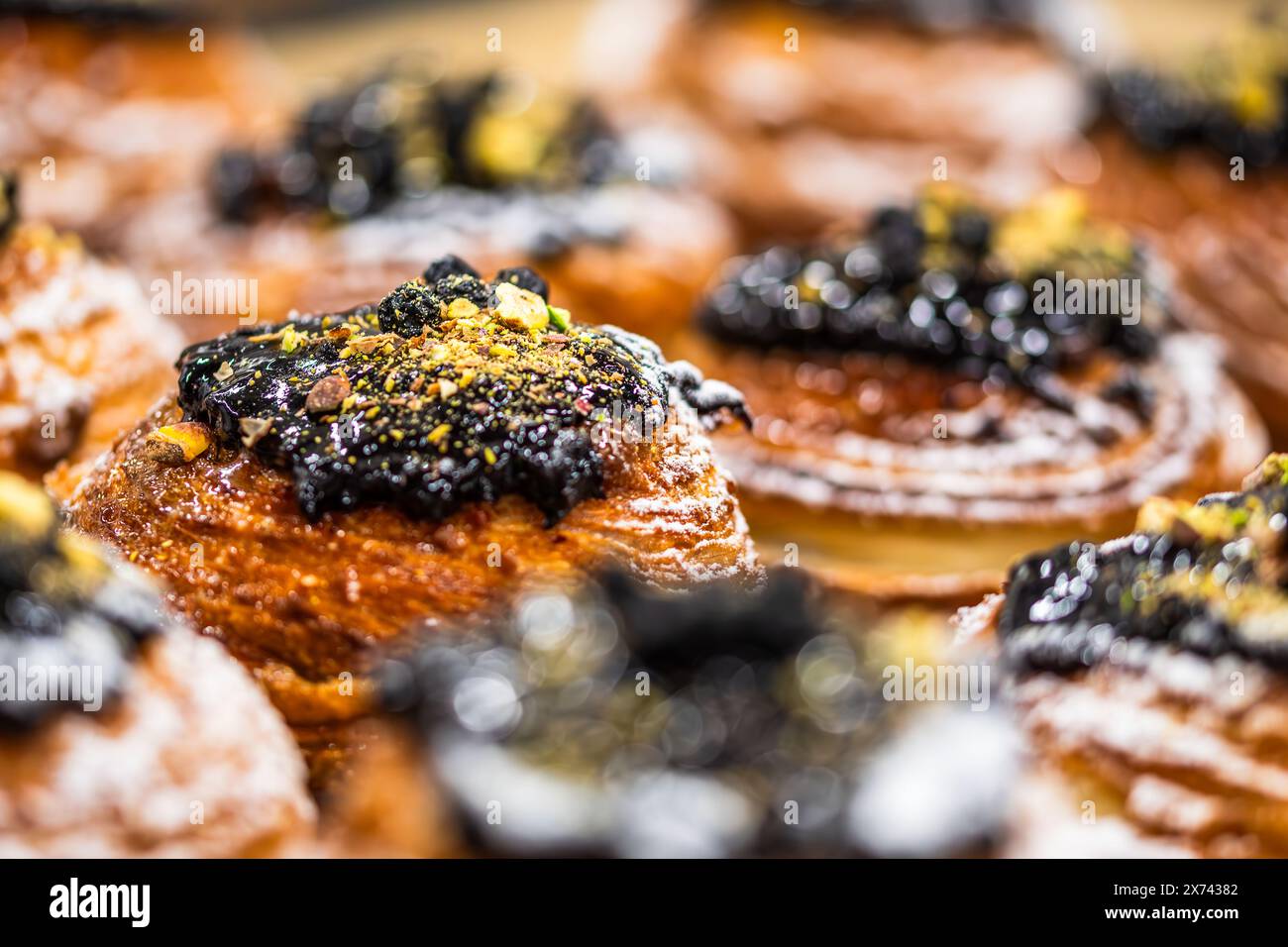 Torta sfoglia con ripieno di mirtilli e pistacchi e noci tritati, sul bancone di una pasticceria, sfondo sfocato Foto Stock