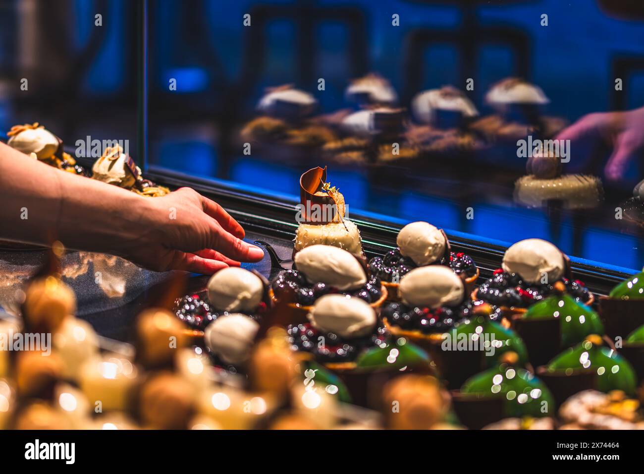 La mano di una fornitrice mette delle crostate smaltate al banco vendite. Preparazione alle vendite al mattino presto. Foto Stock