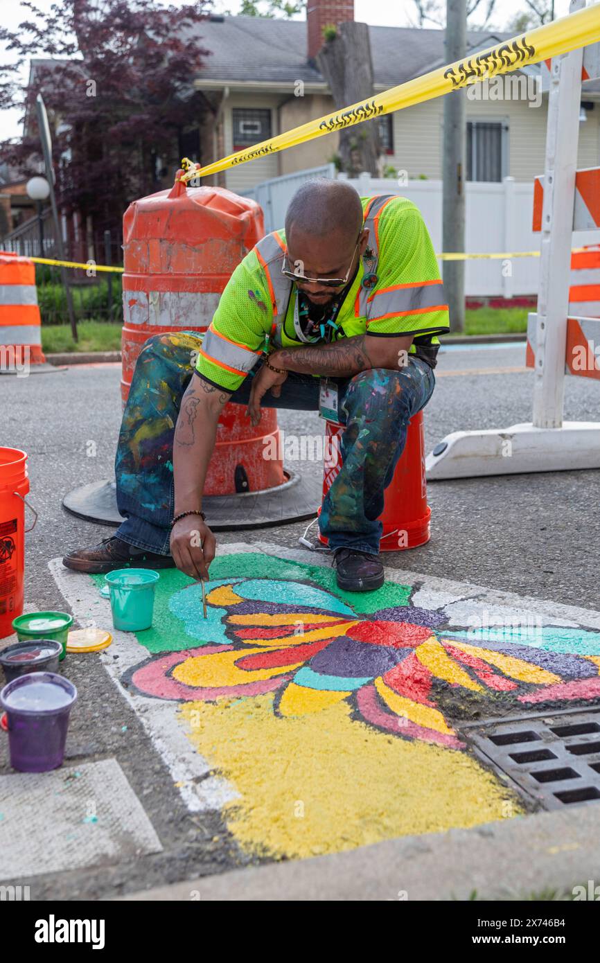 Detroit, Michigan - l'artista Trae Isaac dipinge un design su una strada cittadina. Fa parte di City Walls, un programma cittadino che aggiunge arte al quartiere di Detroit Foto Stock