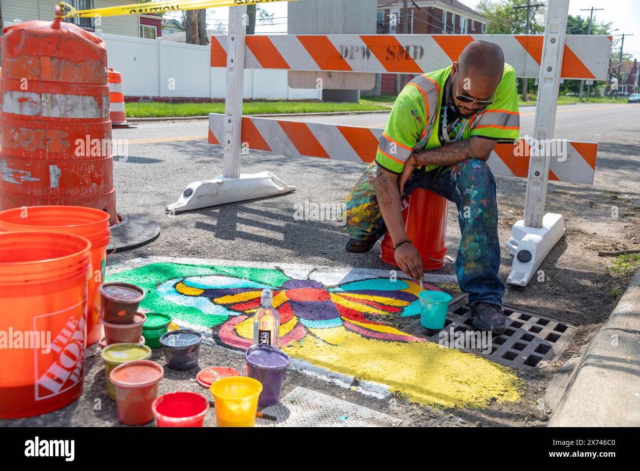 Detroit, Michigan - l'artista Trae Isaac dipinge un design su una strada cittadina. Fa parte di City Walls, un programma cittadino che aggiunge arte al quartiere di Detroit Foto Stock