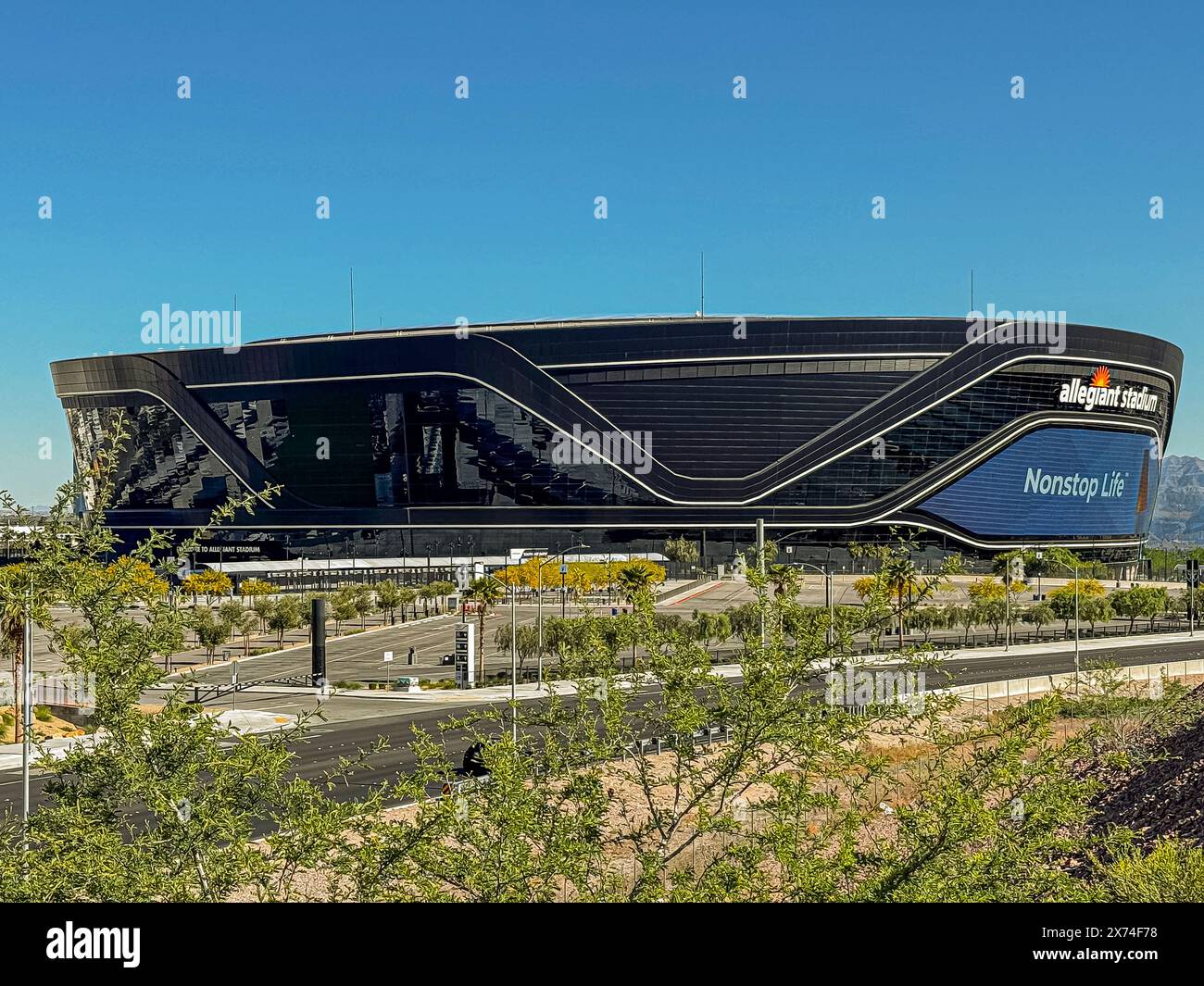 Las Vegas, Nevada, Stati Uniti - 12 maggio 2024: Primo piano dello stadio Black Allegiant con un cartello di salvataggio non stop sotto il cielo blu. Parcheggio vuoto e vegetazione verde Foto Stock