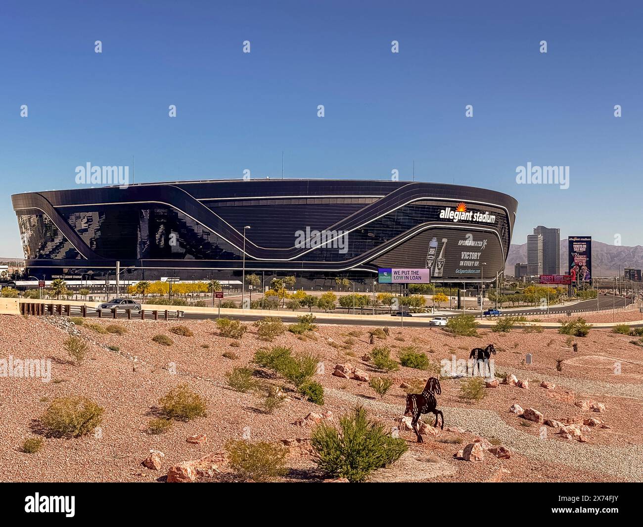 Las Vegas, Nevada, USA - 12 maggio 2024: Primo piano dello stadio Black Allegiant con il cartello Victory Sports Water sotto il cielo blu. Parcheggio vuoto e vegetazione verde Foto Stock