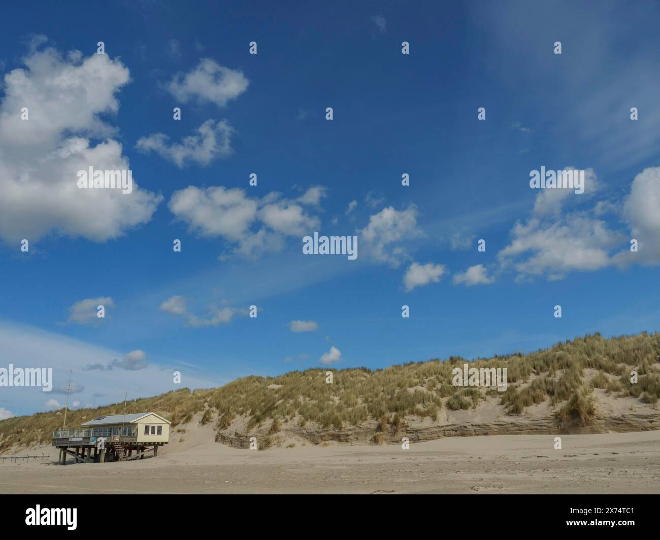 Vista sulla spiaggia con dune erbose e una casa sotto un cielo nuvoloso, nuvole sulla spiaggia con dune sul mare, Hollum, ameland, paesi bassi Foto Stock