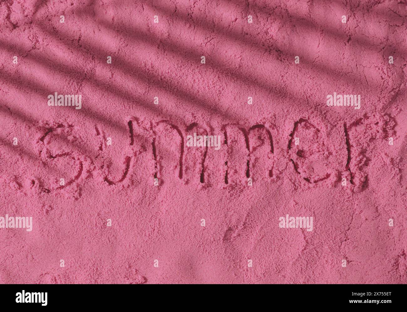 La parola Estate scritta a mano su una superficie di sabbia rosa con ombra tropicale di foglie di palma. Foto minimale delle vacanze estive. Sole e ombre. Foto Stock