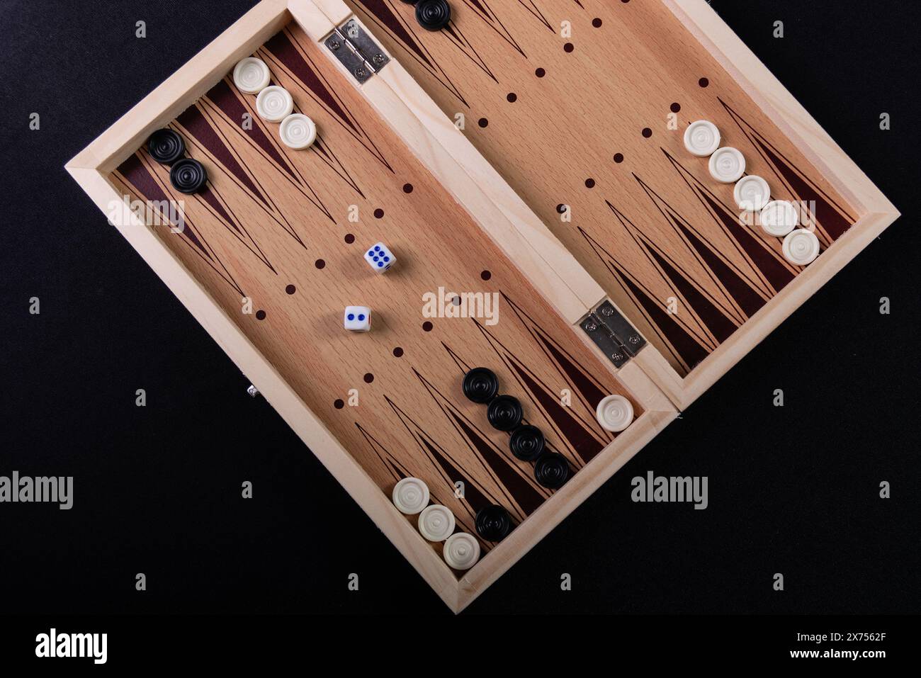 Tabellone per giocare a backgammon con pedine e dadi. Gioco da tavolo, passatempo, divertimento. Su sfondo nero. Foto Stock