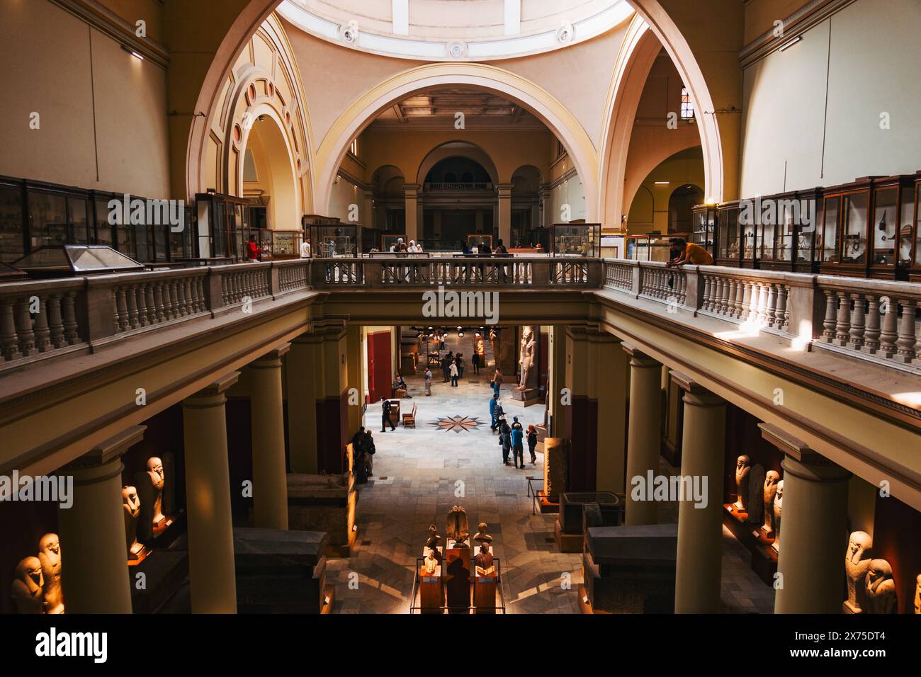 All'interno del Museo Egizio del Cairo, che mostra statue, colonne, soffitti ad arco e visitatori in una grande sala a due piani piena di manufatti Foto Stock