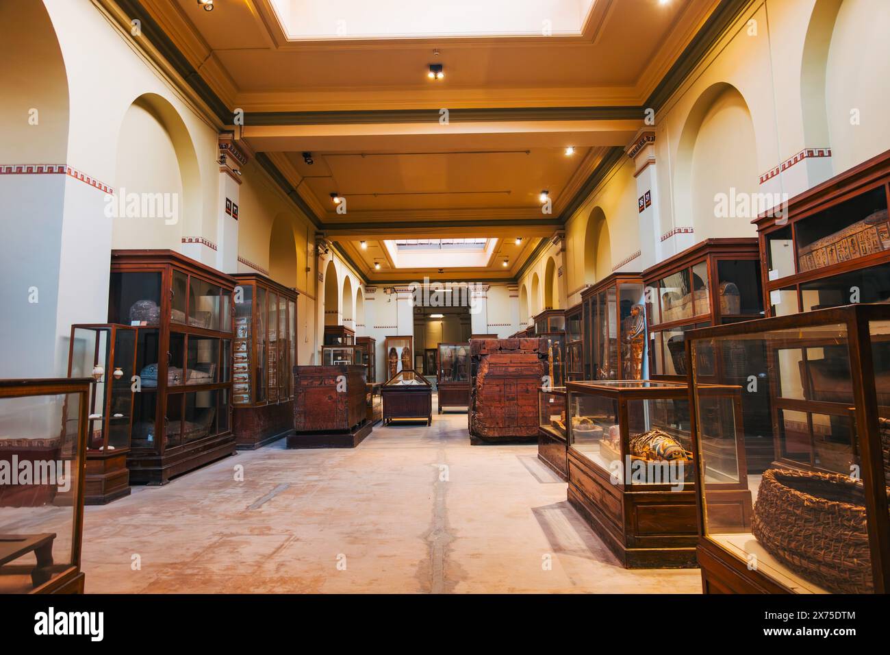 Galleria all'interno del Museo Egizio del Cairo con manufatti in vetrine in legno, soffitti ad arco e luci soffuse che mettono in risalto antichi tesori Foto Stock