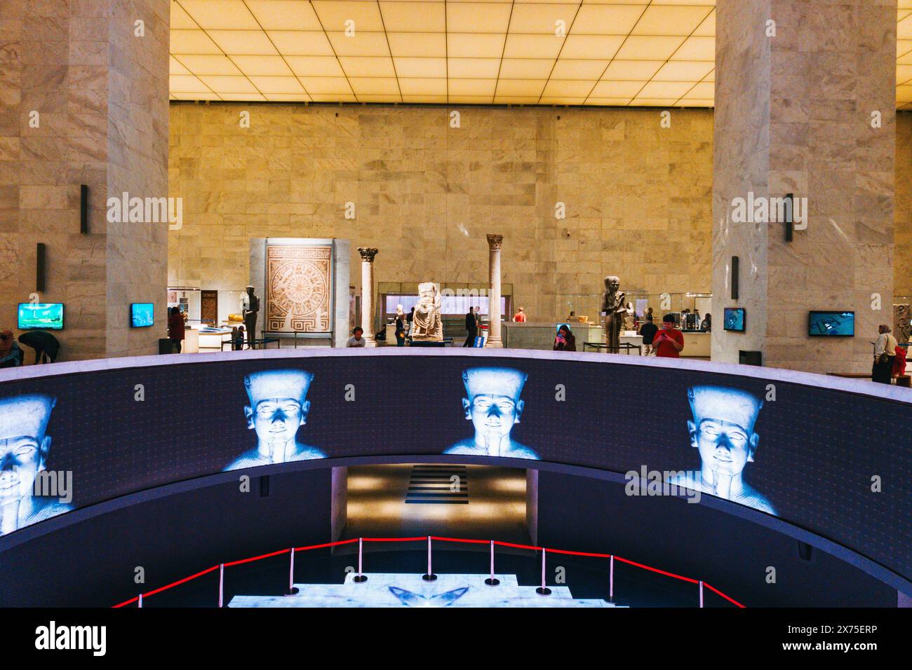 Schermi digitali presso il Museo Nazionale della civiltà Egizia del Cairo, con statue, esposizioni e visitatori sotto un soffitto a griglia illuminato dal cielo Foto Stock
