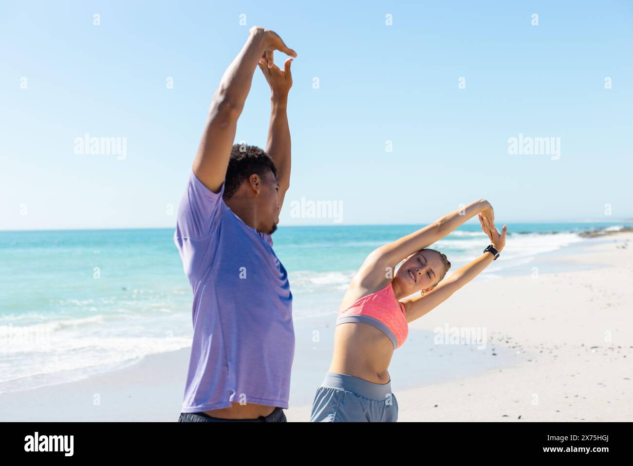 In spiaggia, diverse coppie che si allungano, sia in forma che attiva Foto Stock