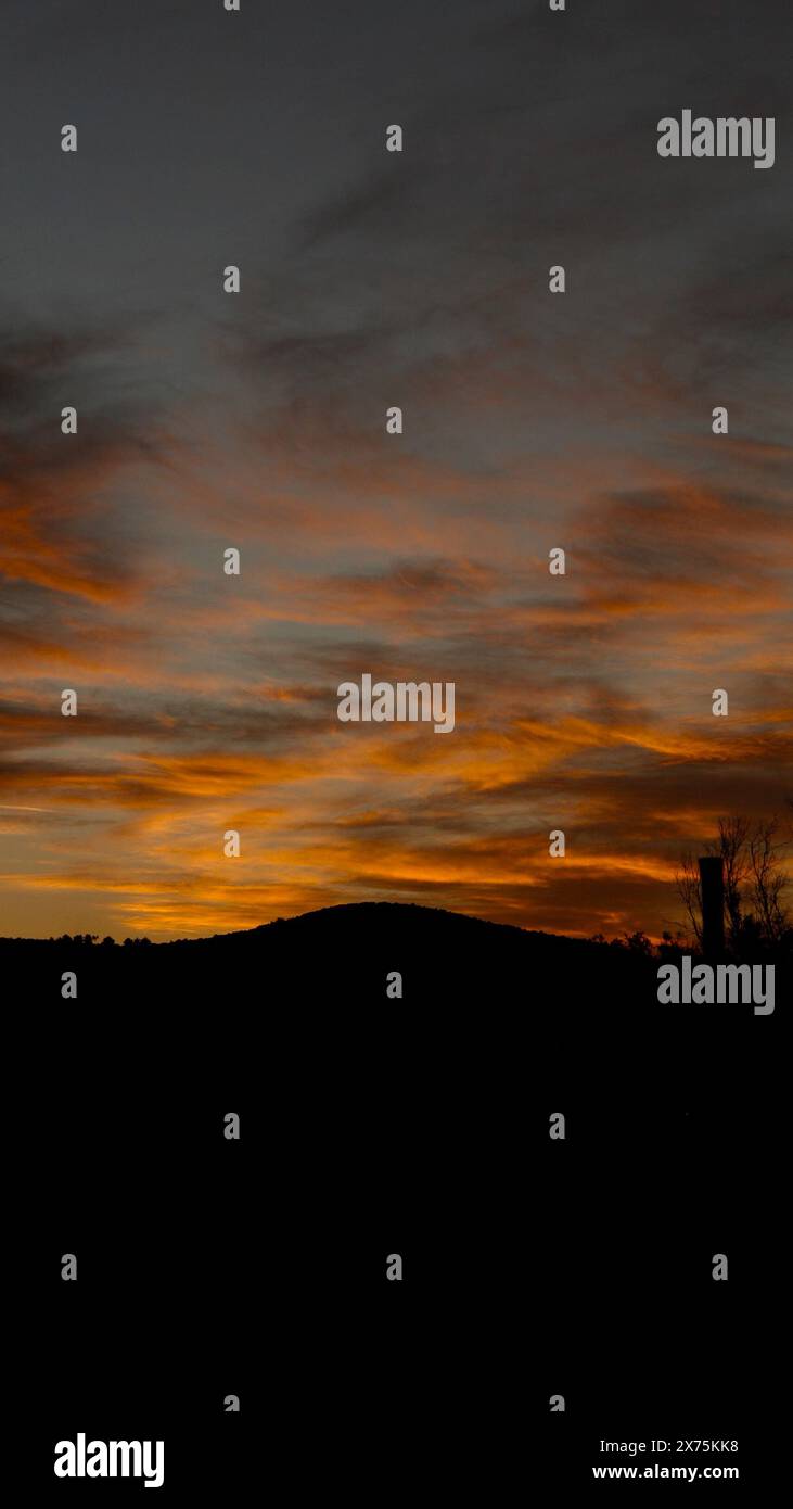 Silhouette con un tramonto nuvoloso Foto Stock