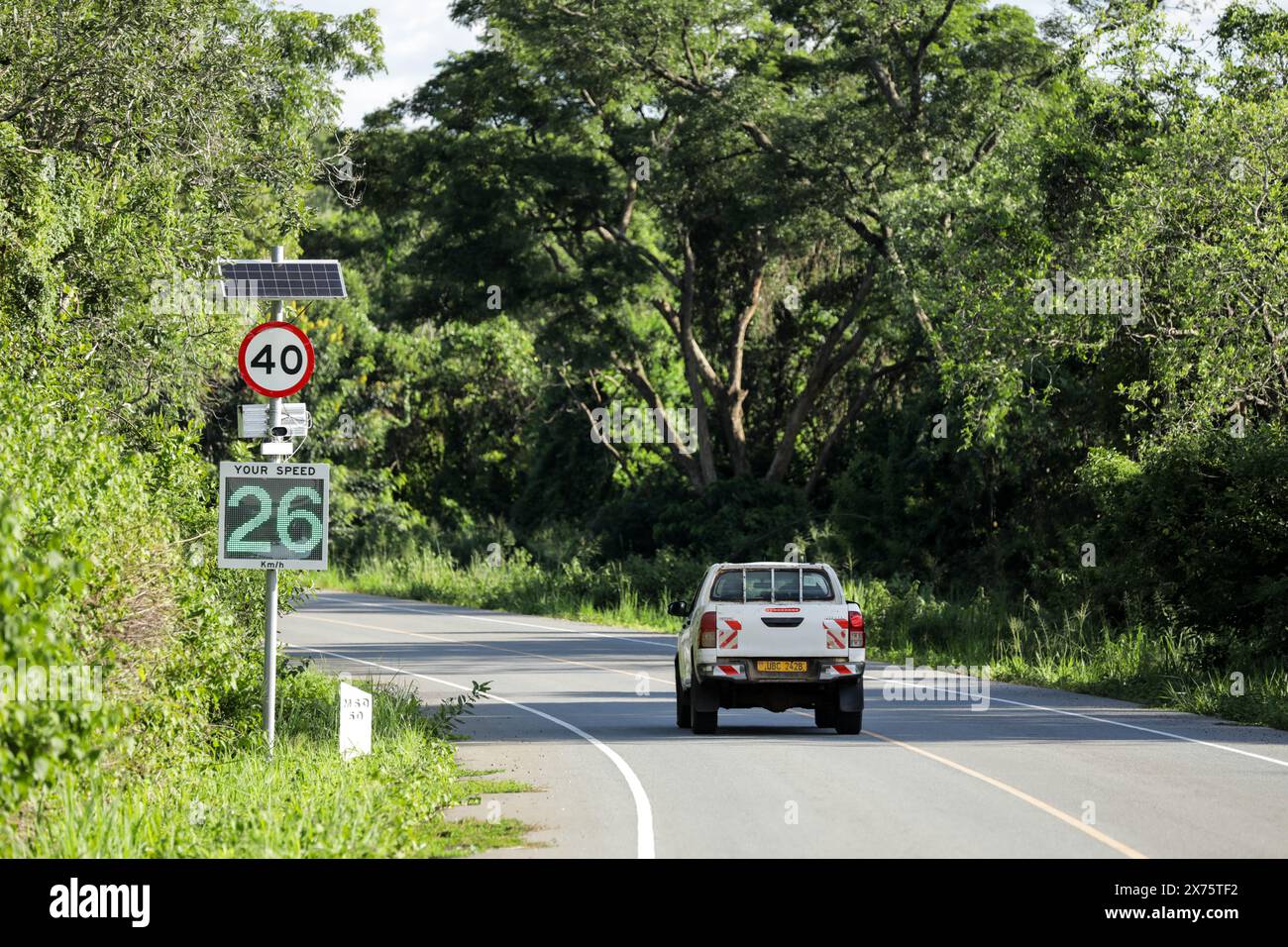 Masindi. 11 maggio 2024. L'11 maggio 2024 un'auto passa davanti a un sensore di velocità su una sezione di una strada costruita in Cina all'interno del Parco Nazionale delle Cascate Murchison, nel nord-ovest dell'Uganda. PER ANDARE CON "Feature: La strada cinese dell'Uganda trasforma le vite, aumenta l'economia" crediti: Hajarah Nalwadda/Xinhua/Alamy Live News Foto Stock
