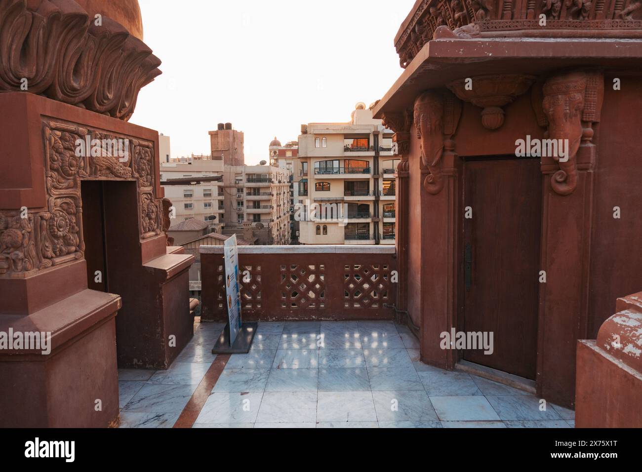 Terrazza sul tetto dello storico palazzo Baron Empain a Heliopolis, con pavimenti in marmo e architettura in arenaria rossa al tramonto Foto Stock