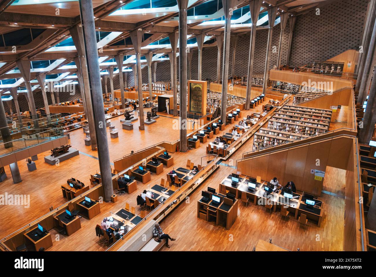 Colonne in cemento e scaffali e scrivanie in legno all'interno della Bibliotheca Alexandrina, una vasta biblioteca ad Alessandria, in Egitto Foto Stock