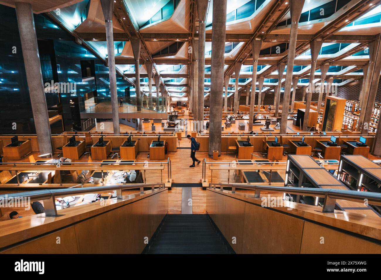 Colonne in cemento e scaffali e scrivanie in legno all'interno della Bibliotheca Alexandrina, una vasta biblioteca ad Alessandria, in Egitto Foto Stock
