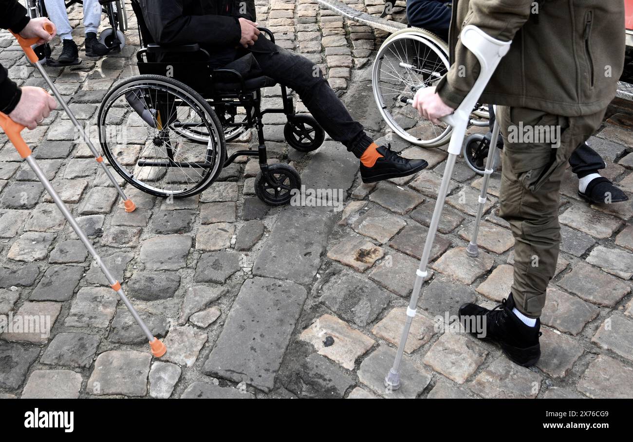 un uomo con gambe amputate su una sedia a rotelle ai ciottoli. inclusività Foto Stock