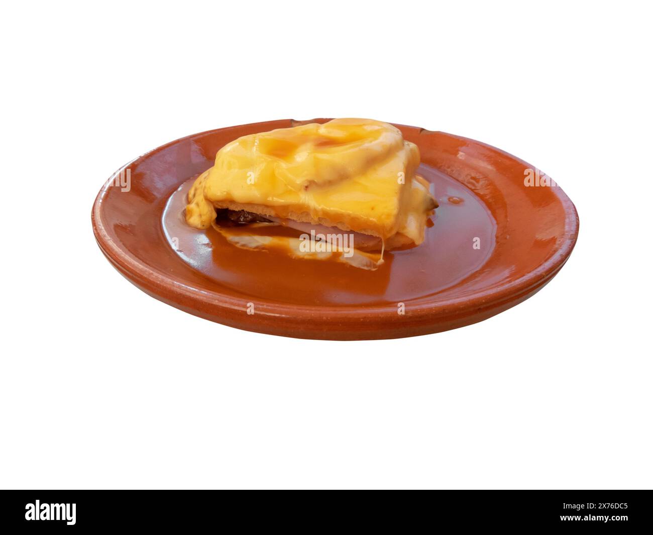 Francesinha nella piastra in ceramica isolata su bianco. Panino portoghese a strati di pane tostato e prosciutto, chipolata e formaggio con pomodoro e Foto Stock