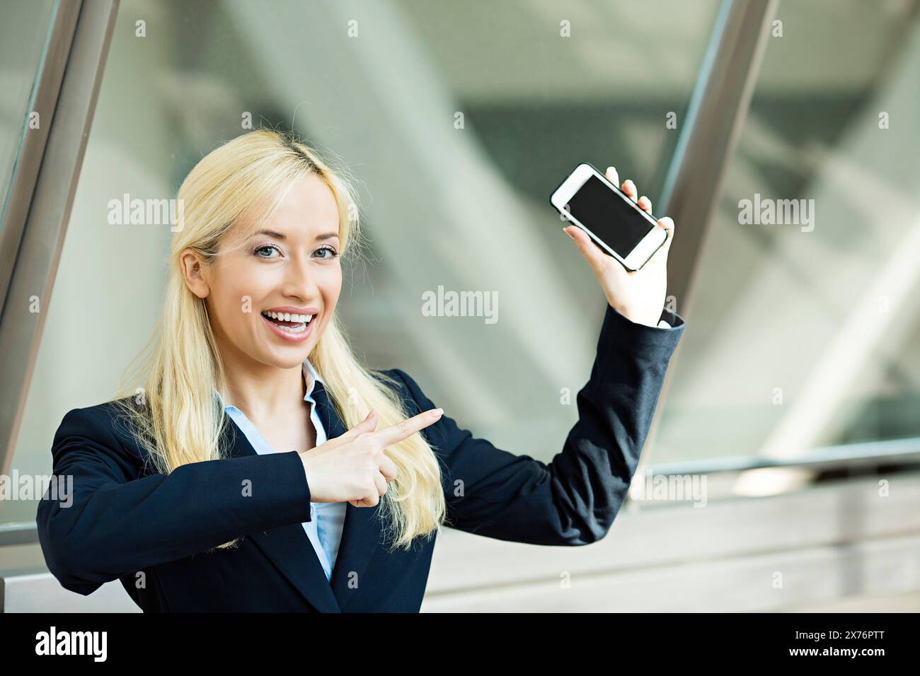 Felice donna d'affari che punta con il dito il telefono cellulare Foto Stock