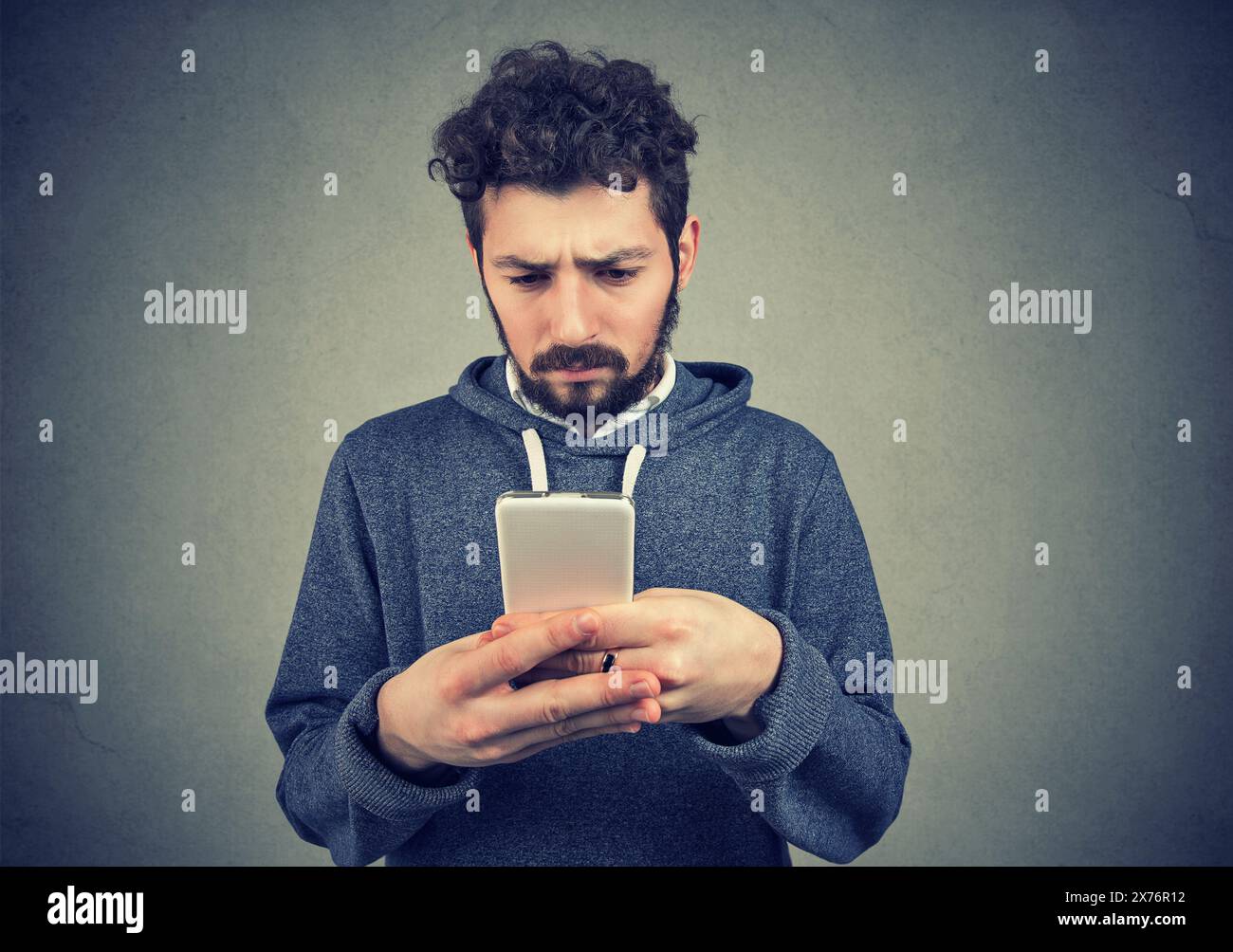 Un giovane preoccupato che controllava il telefono cellulare leggendo cattive notizie Foto Stock