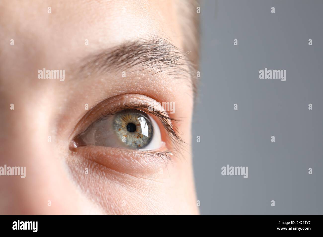 Visione perfetta. Uomo con bellissimi occhi su sfondo grigio, primo piano. Spazio per il testo Foto Stock